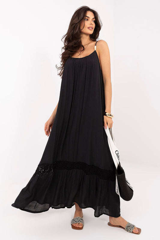 Mujer con vestido largo negro de algodón estilo ibicenco con detalles de cuentas en tirantes y encaje en el bajo de Naiala Moda.