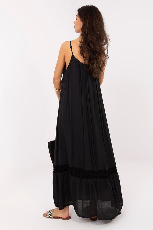 Mujer con vestido largo negro de algodón estilo ibicenco con detalles de cuentas en tirantes y encaje en el bajo de Naiala Moda.